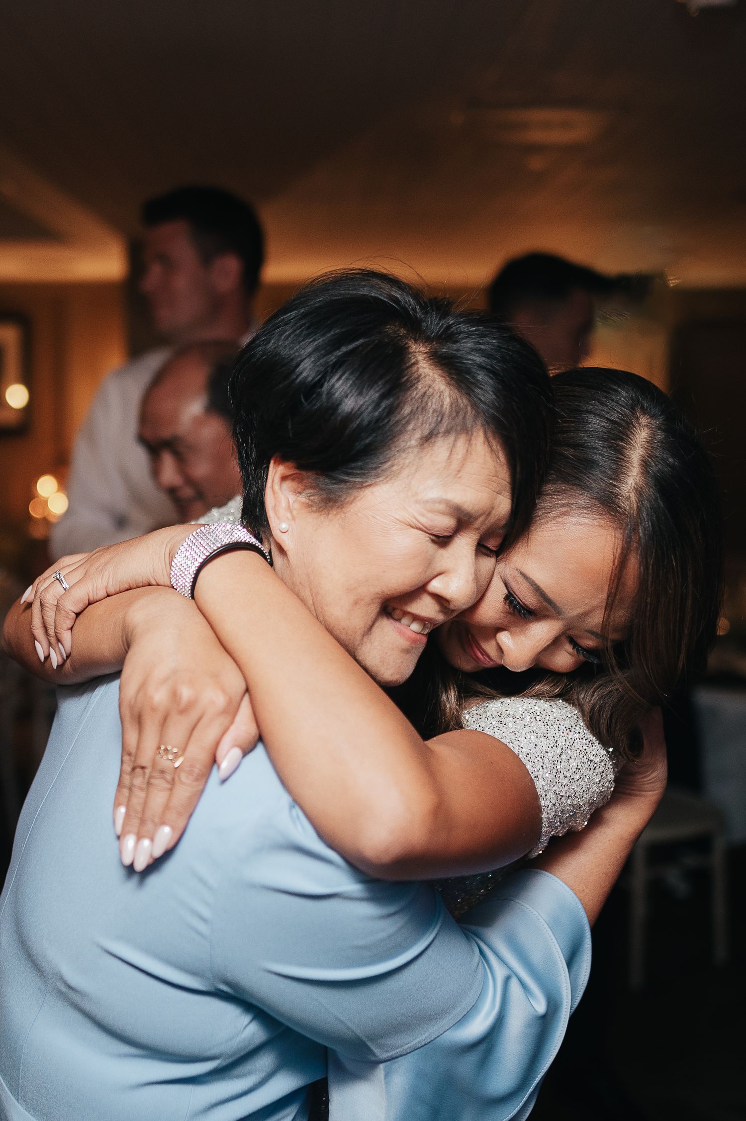 Emotional embrace captured during wedding reception celebration.