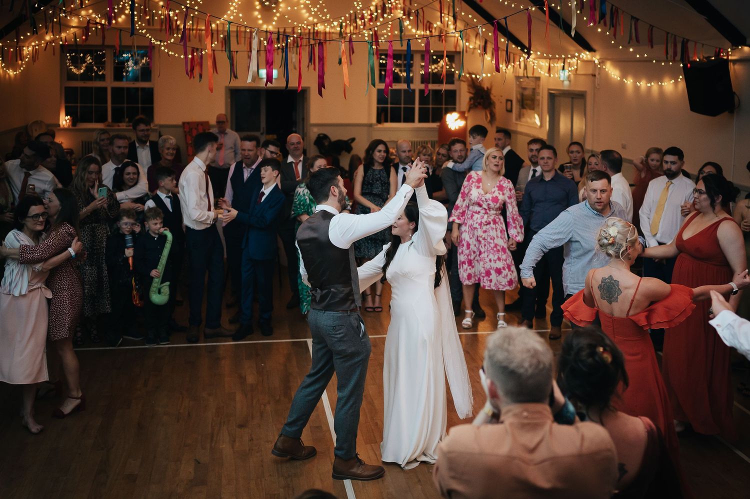 A couple performs their first dance while guests watch at a wedding reception.