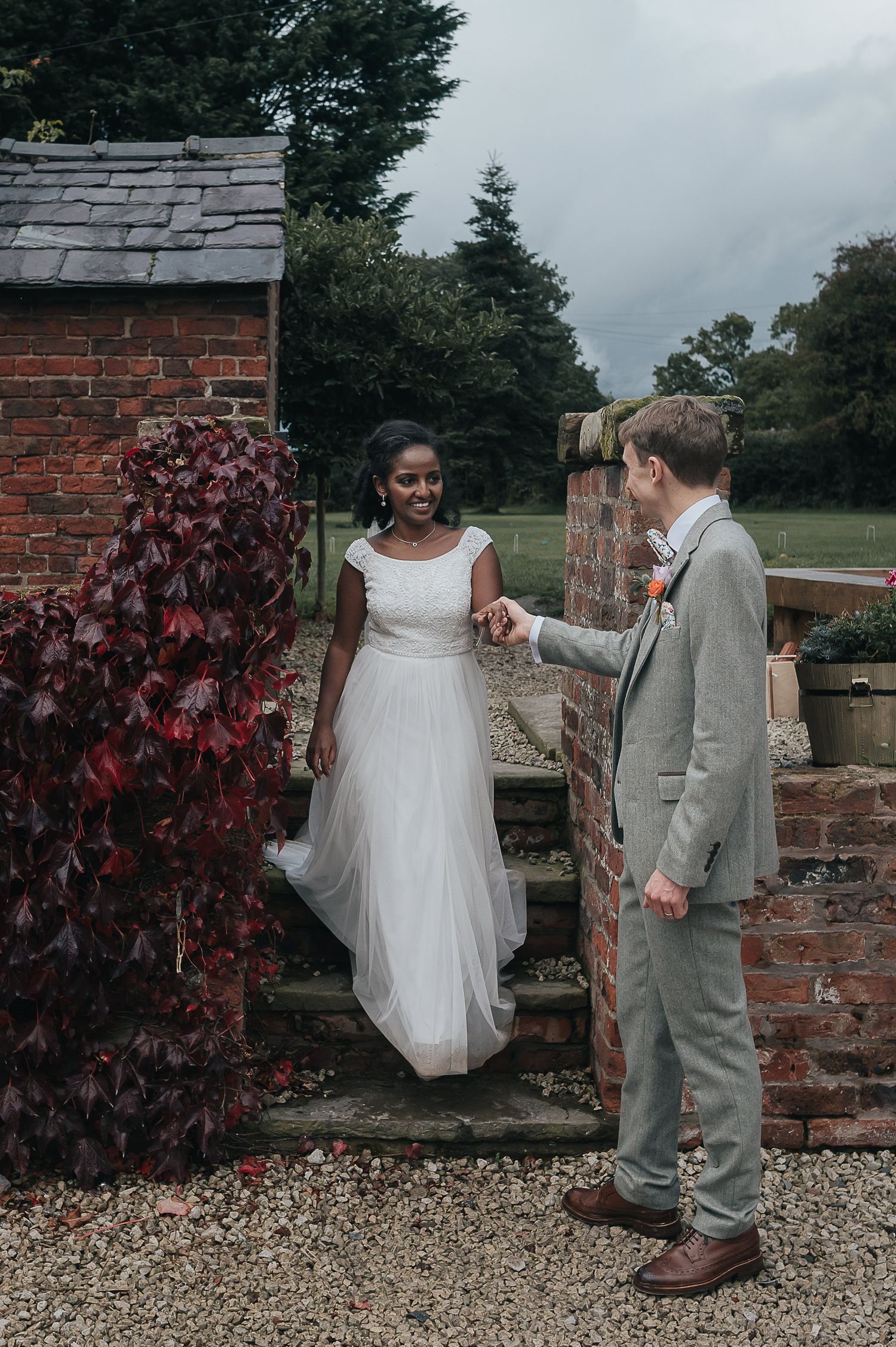 A wedding couple sharing a moment on brick steps covered with red ivy.