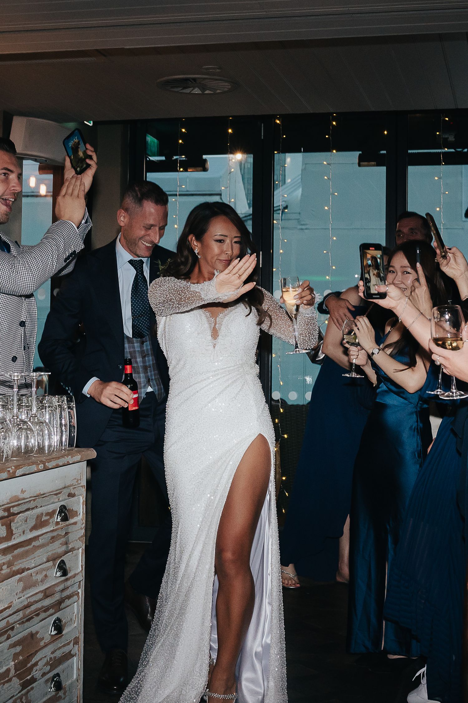 Wedding celebration with guests dancing and cheering in a festive venue.