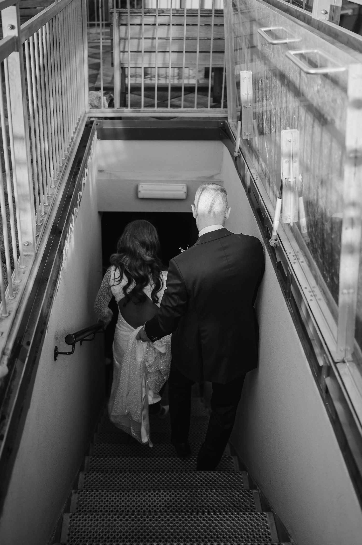 Couple descends staircase together in black and white photography.