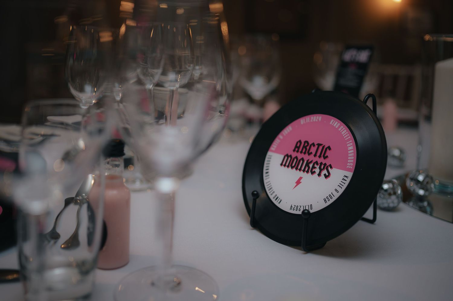 Black vinyl record Arctic Monkeys album displayed on white surface with blurred background decorations.