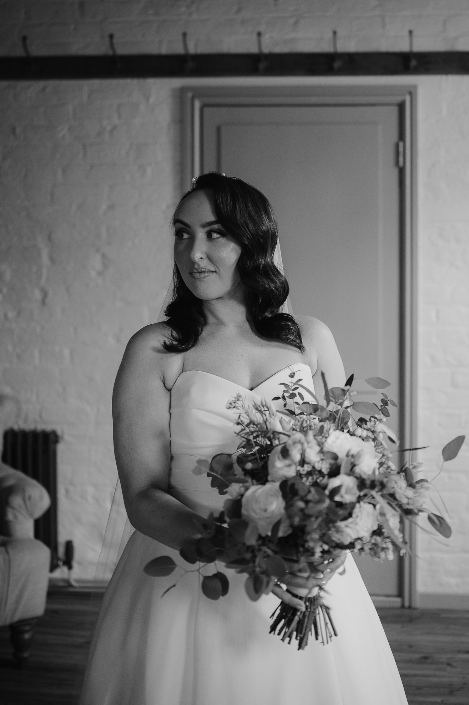 Bride in strapless gown holds a romantic bouquet with eucalyptus and flowers.