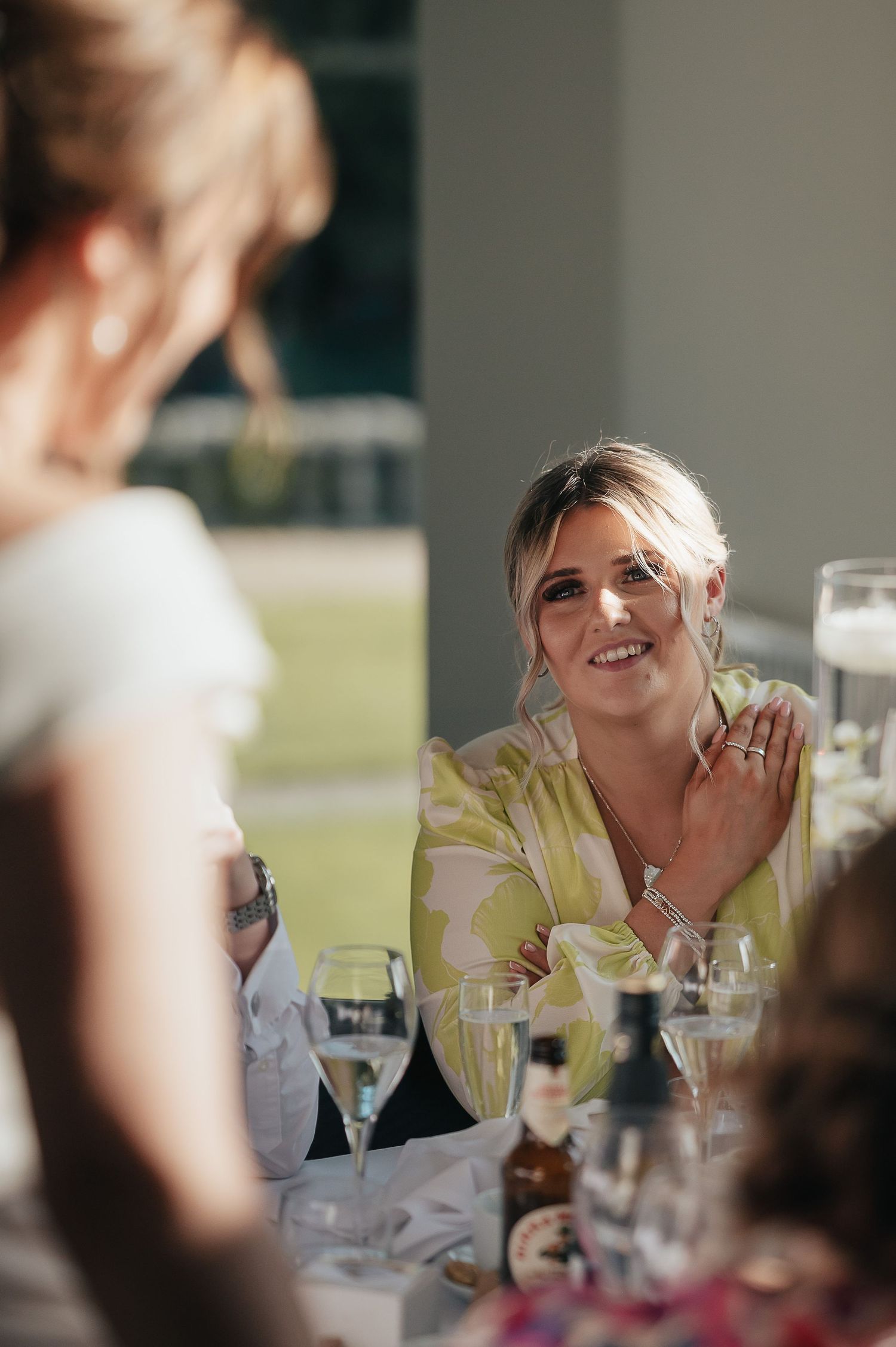 Wedding guest sharing a joyful moment at an elegant reception dinner with wine glasses on the table.