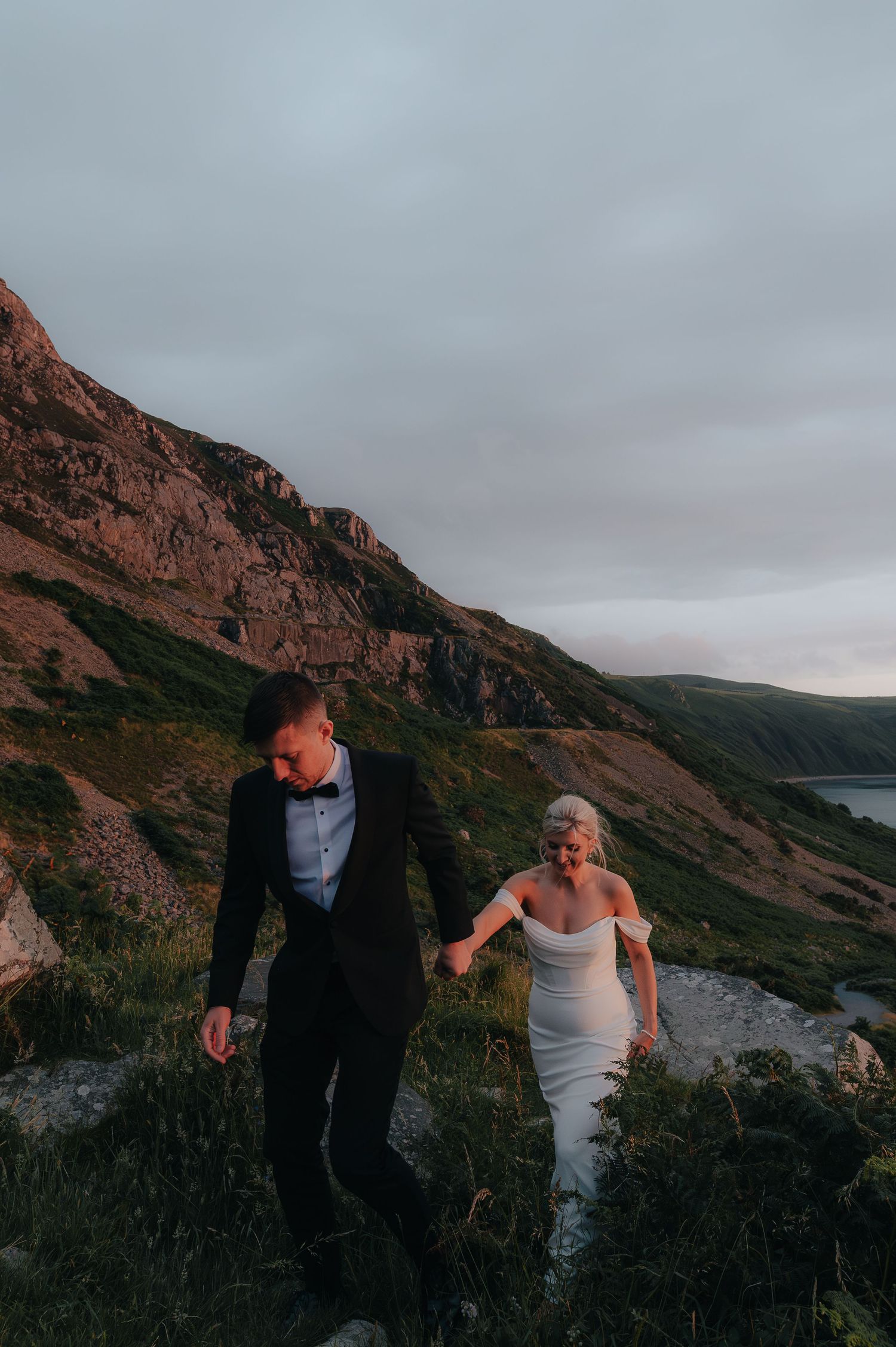 Rugged coastal cliffs and mountains create a dramatic backdrop against an overcast sky.