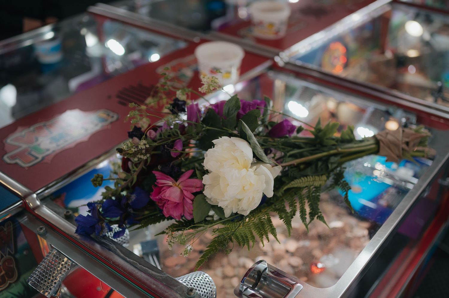 Wedding floral arrangement with white and purple flowers displayed on a mirrored surface.