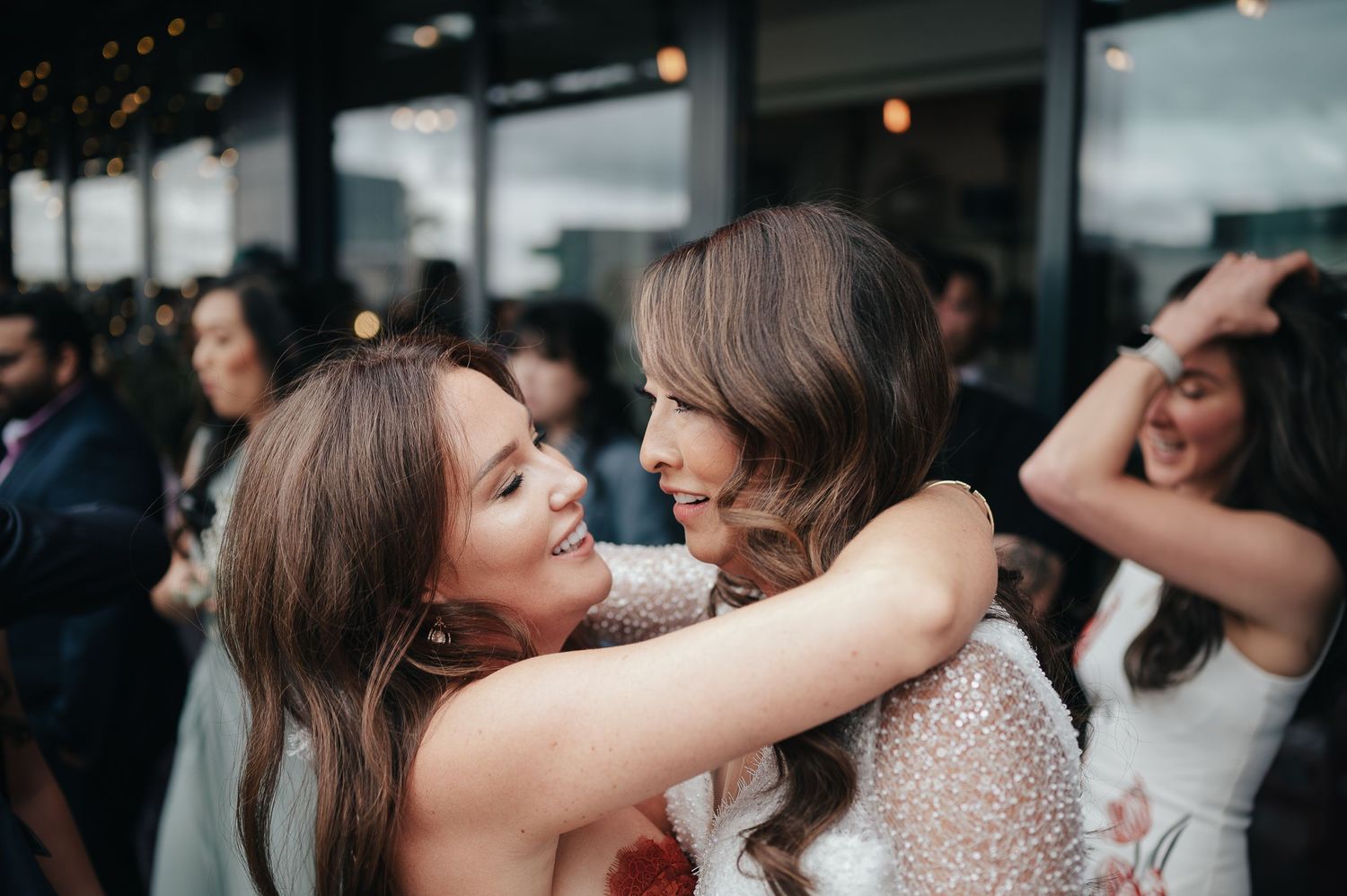 Emotional embrace shared between wedding guests during reception celebration.