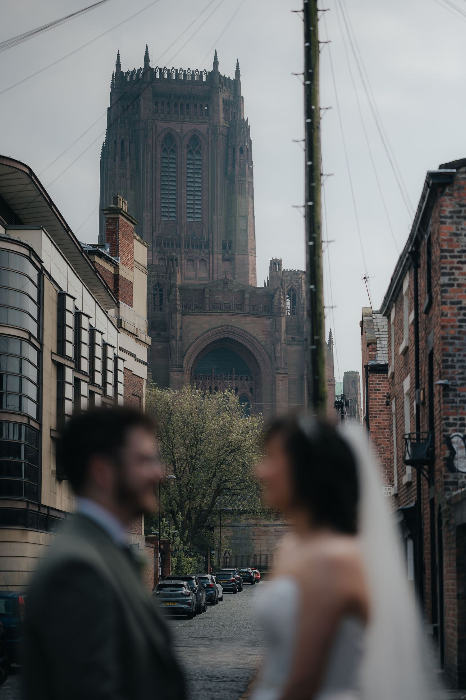 A dramatic cathedral tower looms over a city street creating a stunning wedding photo backdrop.