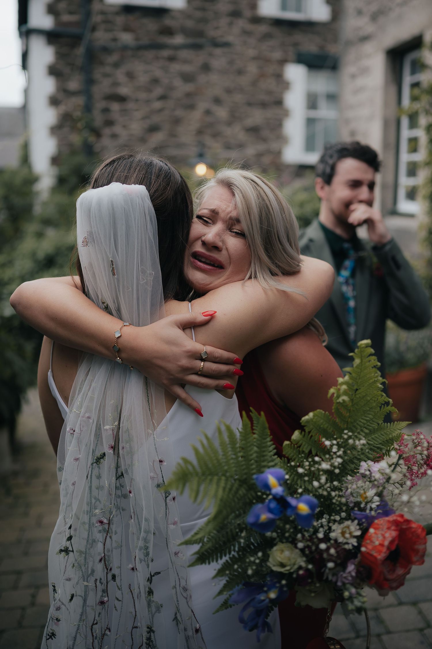 An emotional embrace during a wedding celebration with colorful flowers.