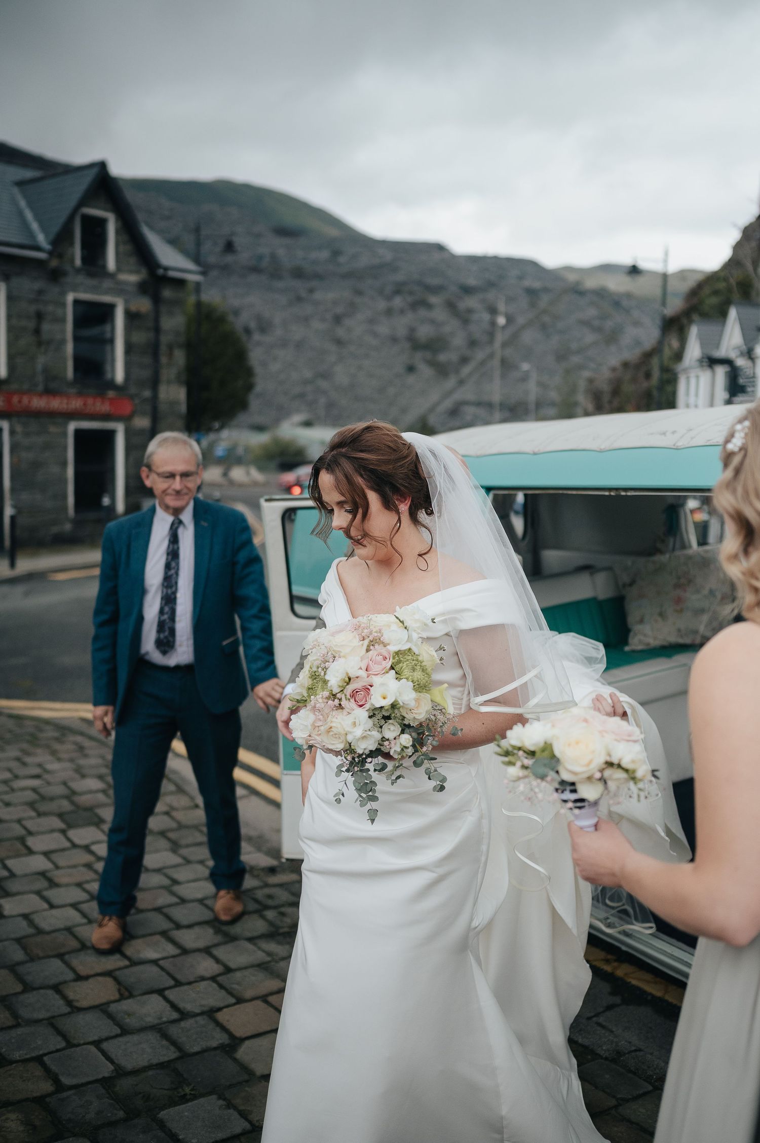 Classic car and cobblestone street wedding scene in mountain town.