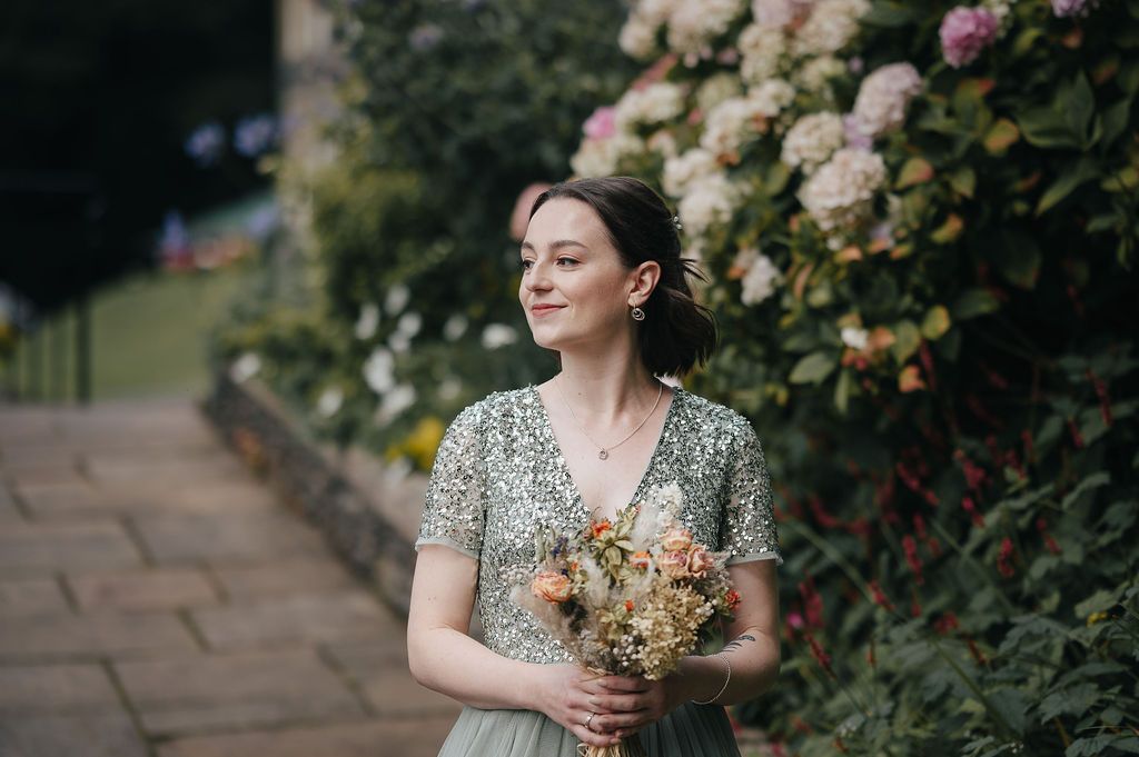 Romantic portrait in garden setting with blooming roses and vintage-inspired attire.