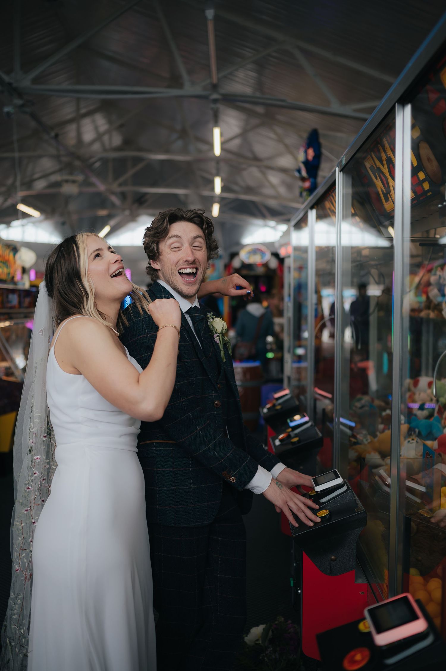 Wedding couple enjoying arcade games and laughing together.