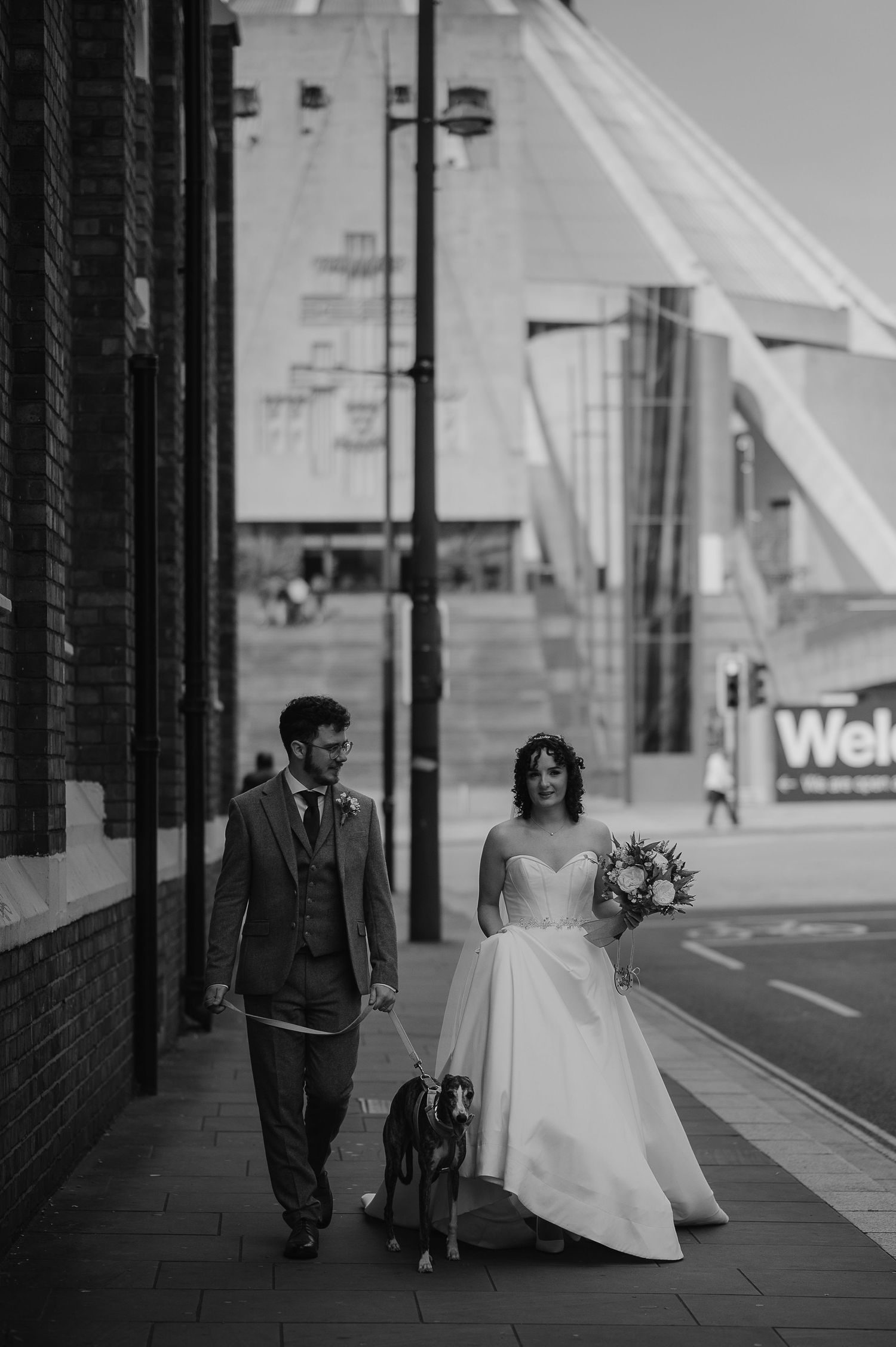 A couple walking down a city street with the Liverpool Cathedral in the background.