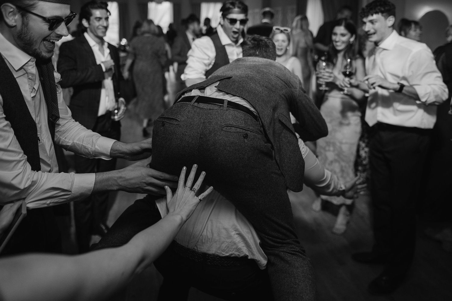 Black and white photo of lively dance floor action at a wedding reception.