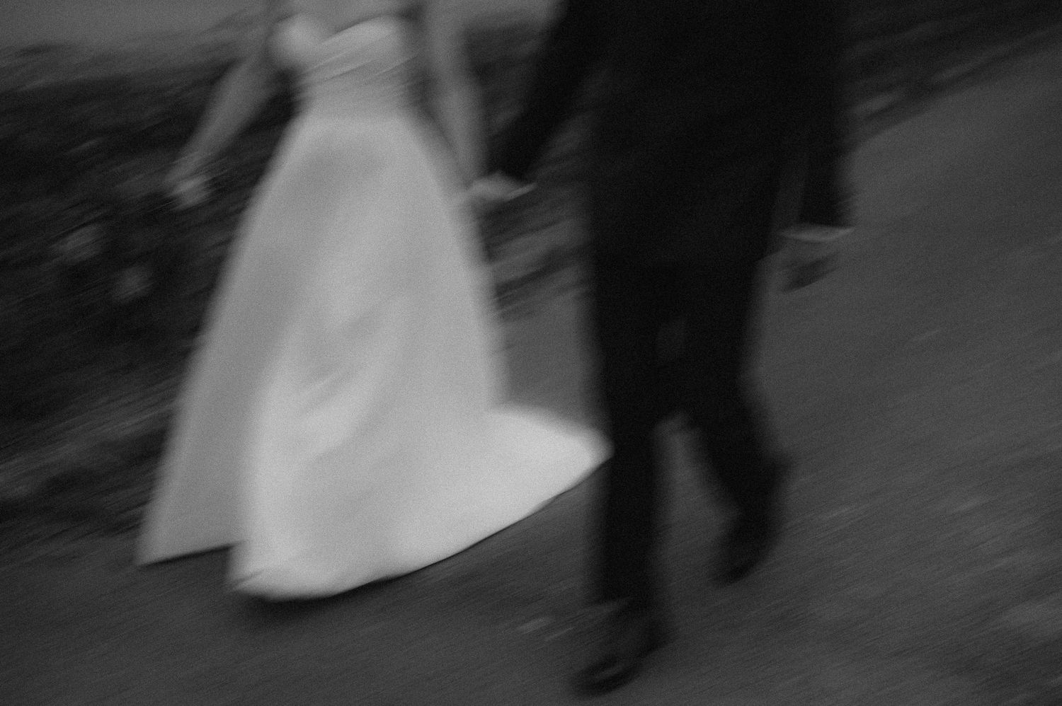 An artistic motion blur capture of a bride and groom walking together.