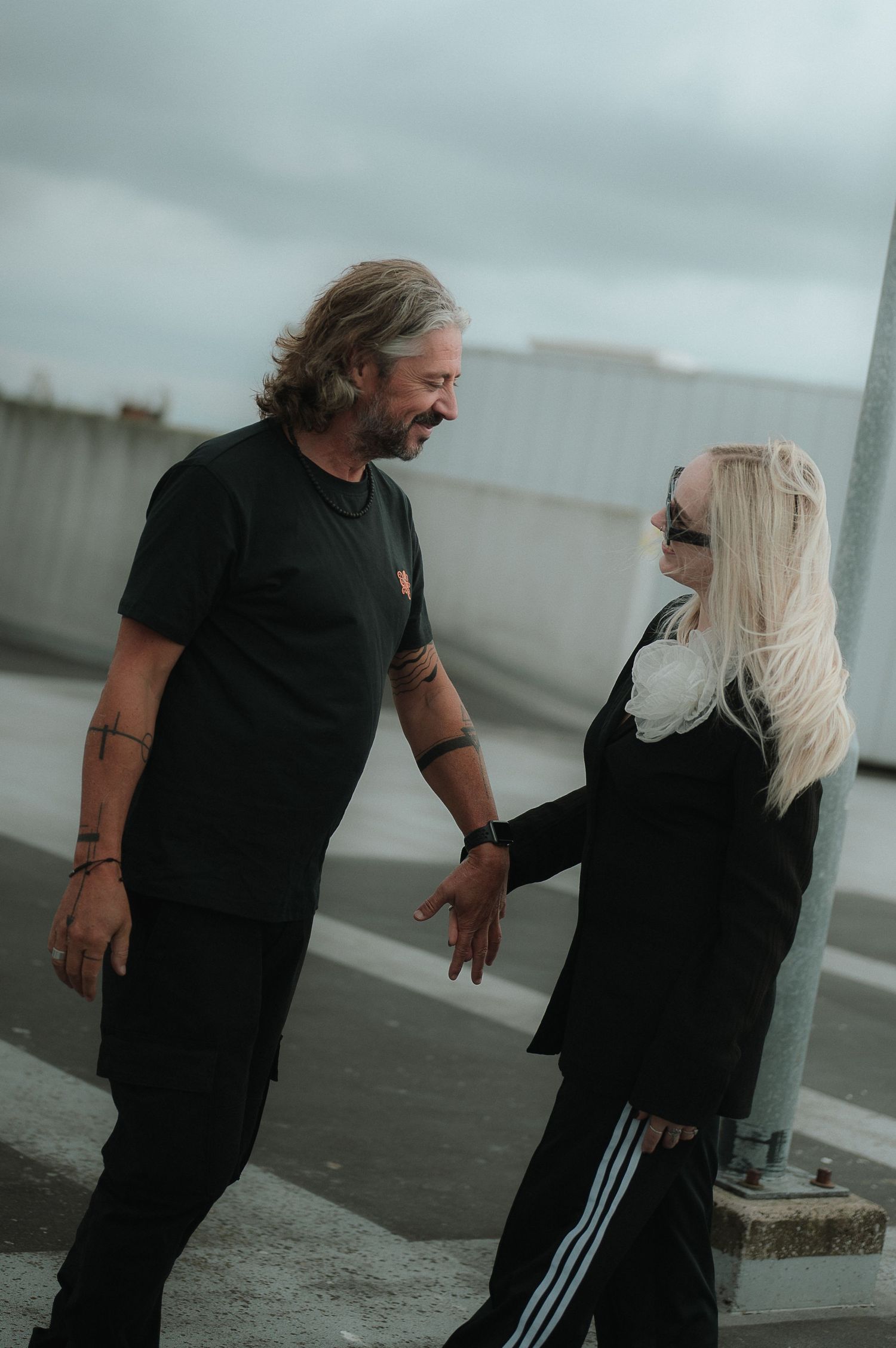 Two people in black clothing interact in a dramatic sequence of poses against a minimalist gray background.