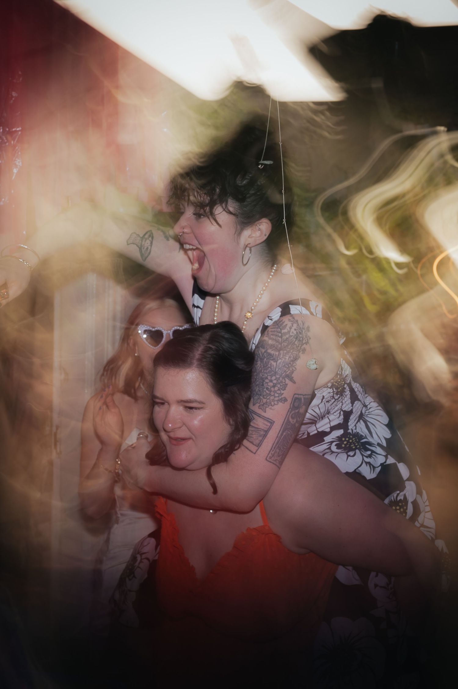 Energetic party scene with people laughing and embracing in atmospheric lighting.