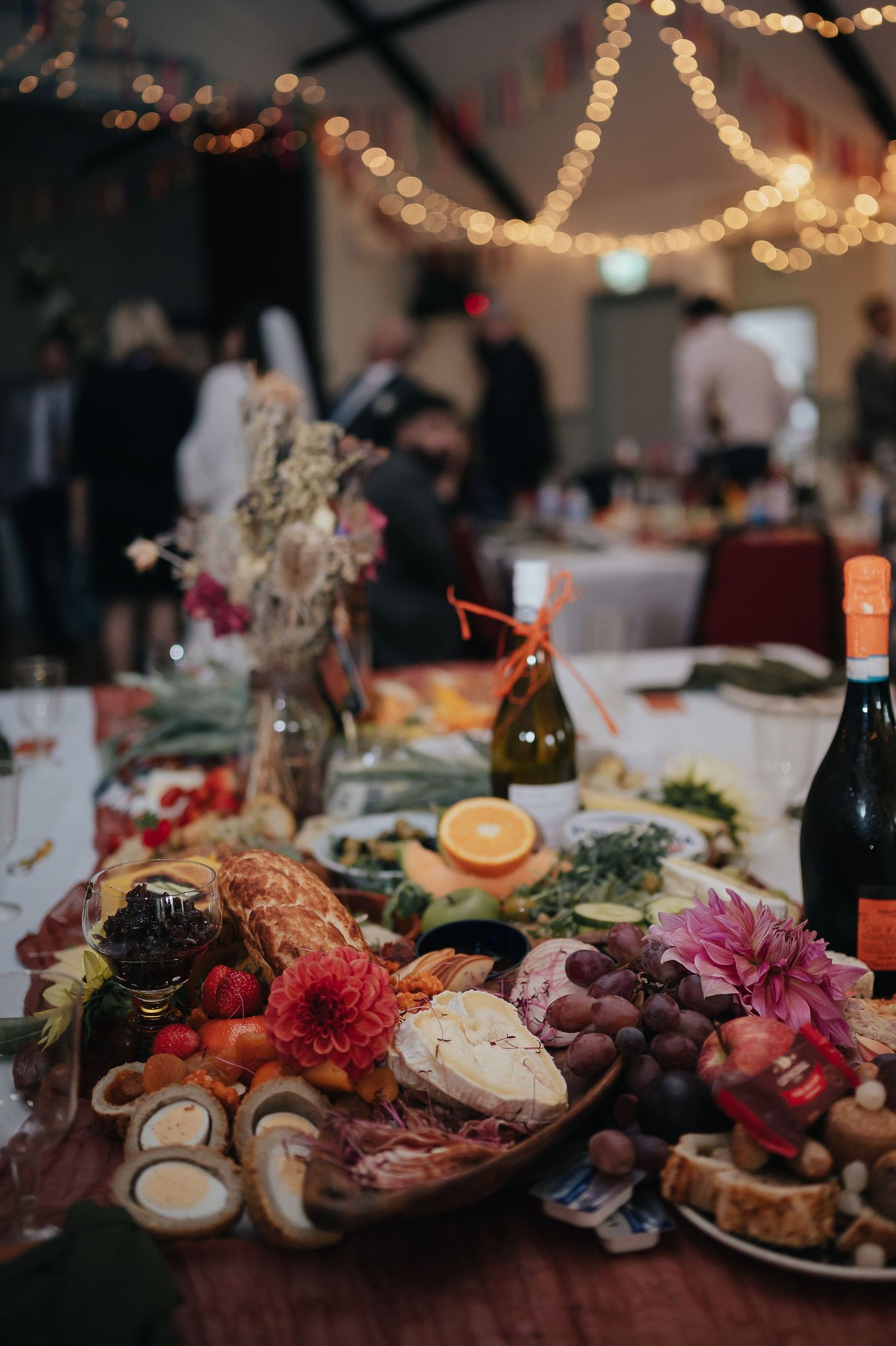 Elegant wedding reception table with charcuterie board, wine and string lights.