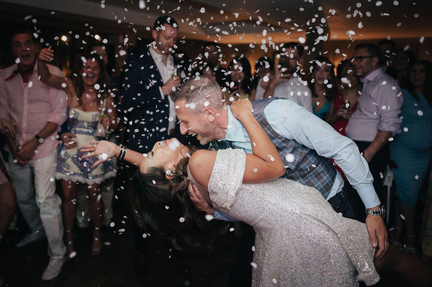 Romantic dip pose on dance floor with glittering confetti falling all around.