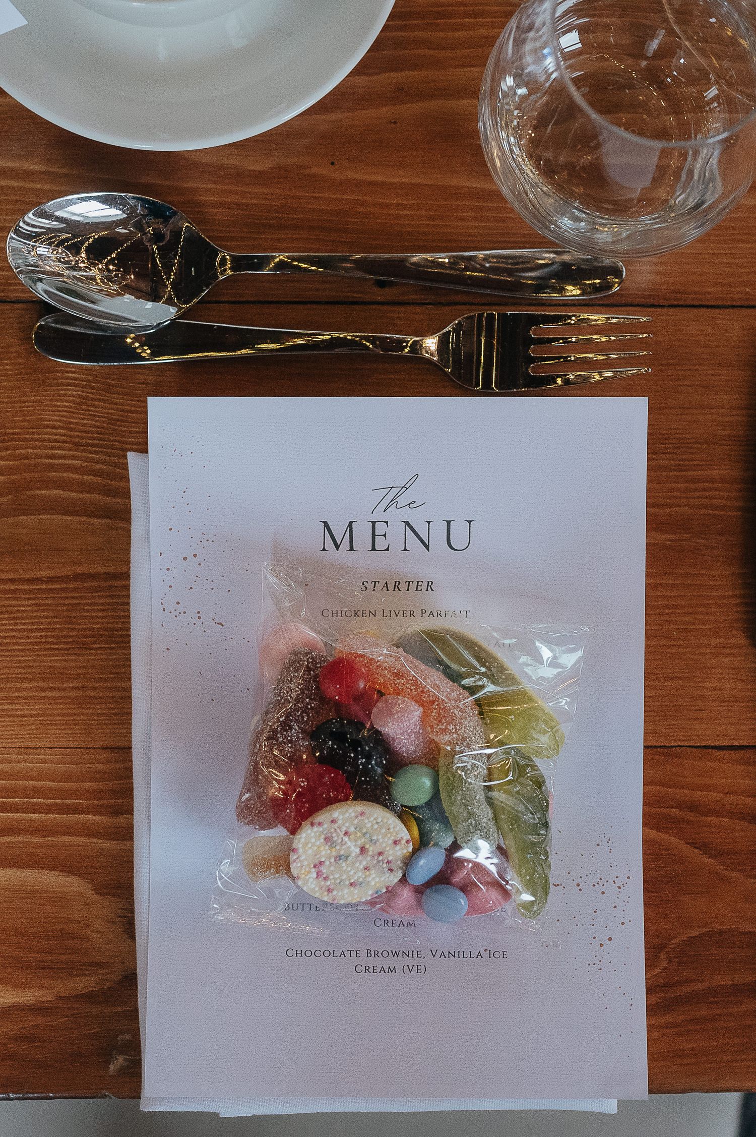 An elegant wedding menu card displayed with silverware on a wooden table.
