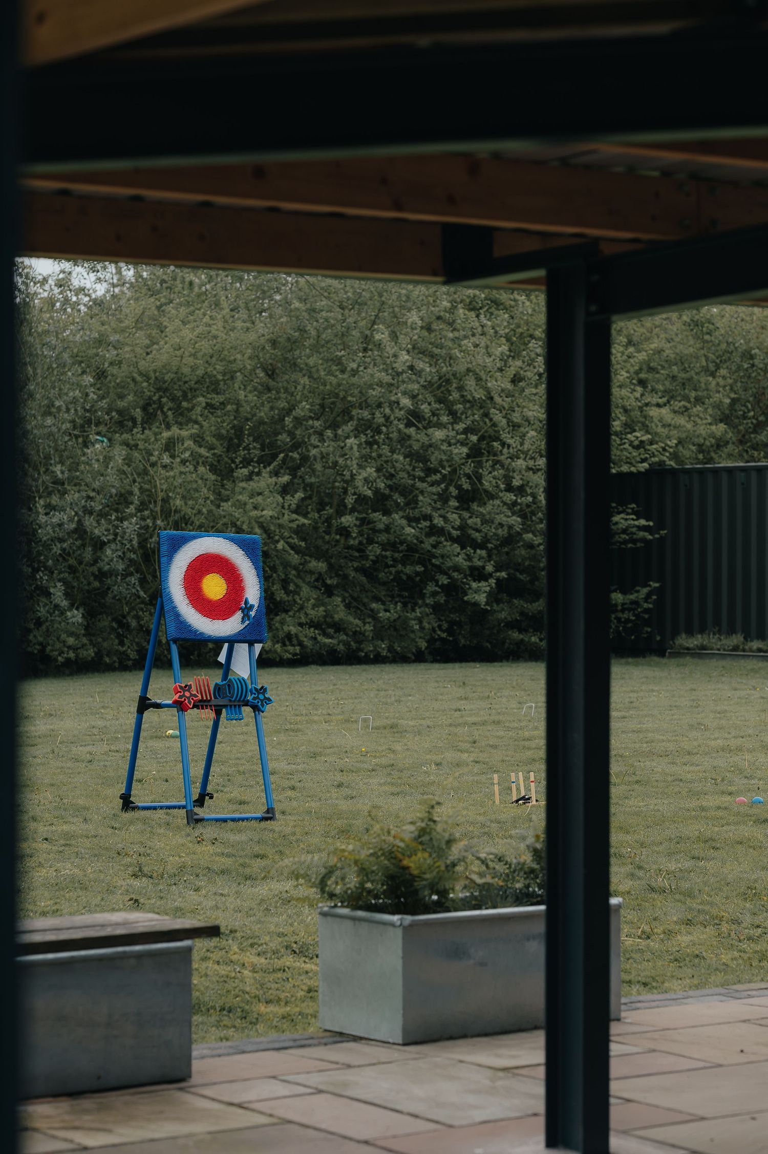 Archery target standing in a green garden viewed through a window frame.