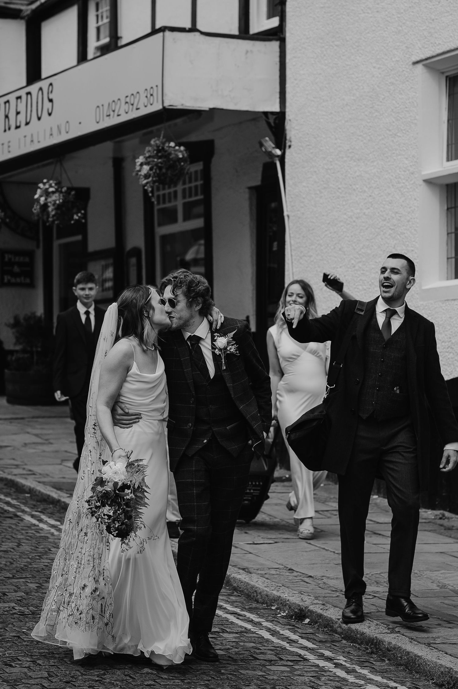 Wedding party walking down street in formal attire, showing candid joyful moment.