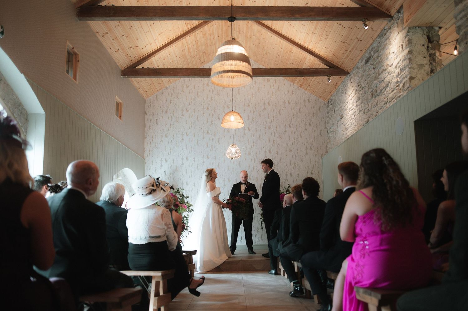 Wedding reception venue interior with exposed beams and pendant lighting.
