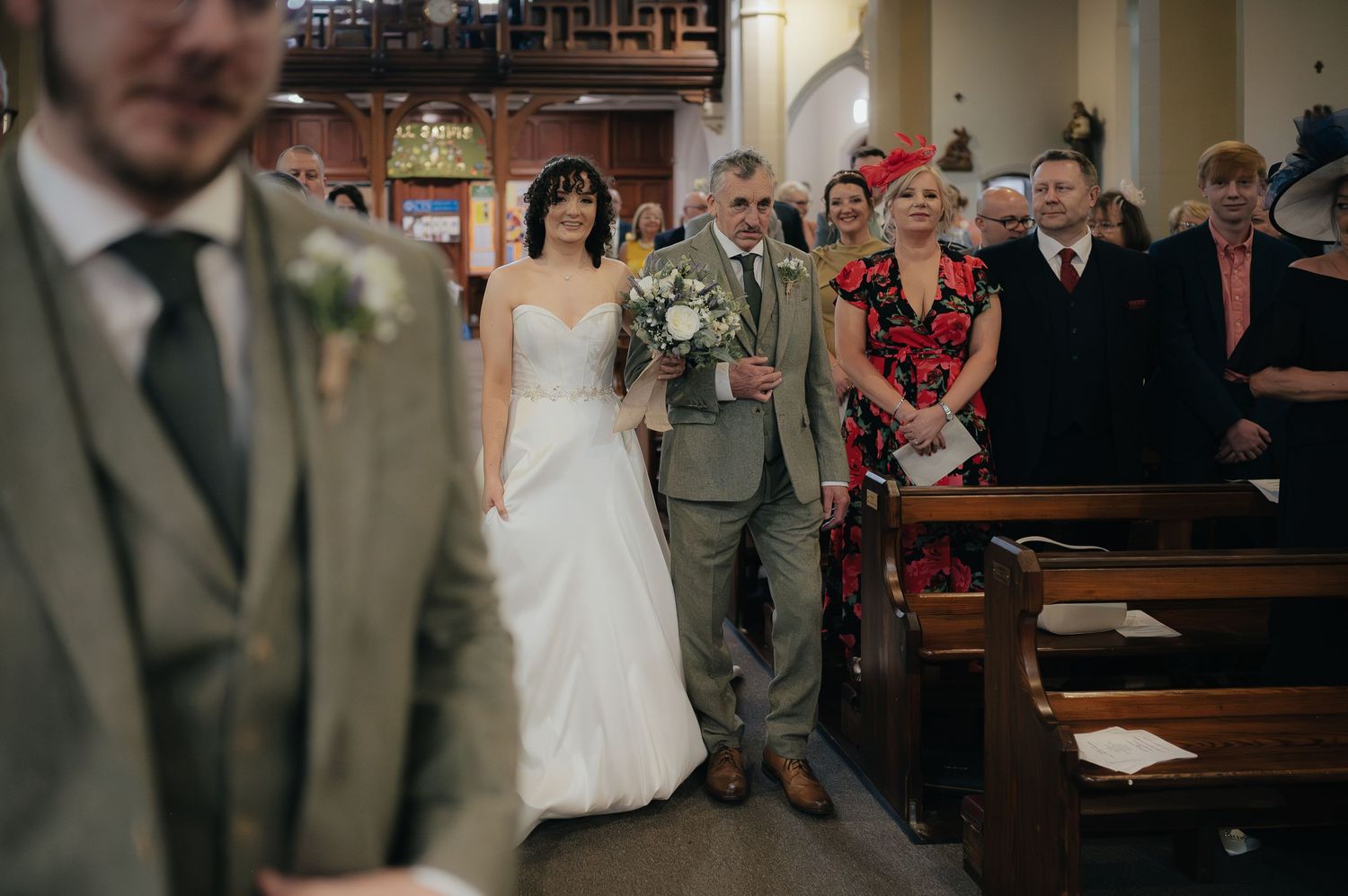 A wedding ceremony in progress inside a traditional church with wooden pews.