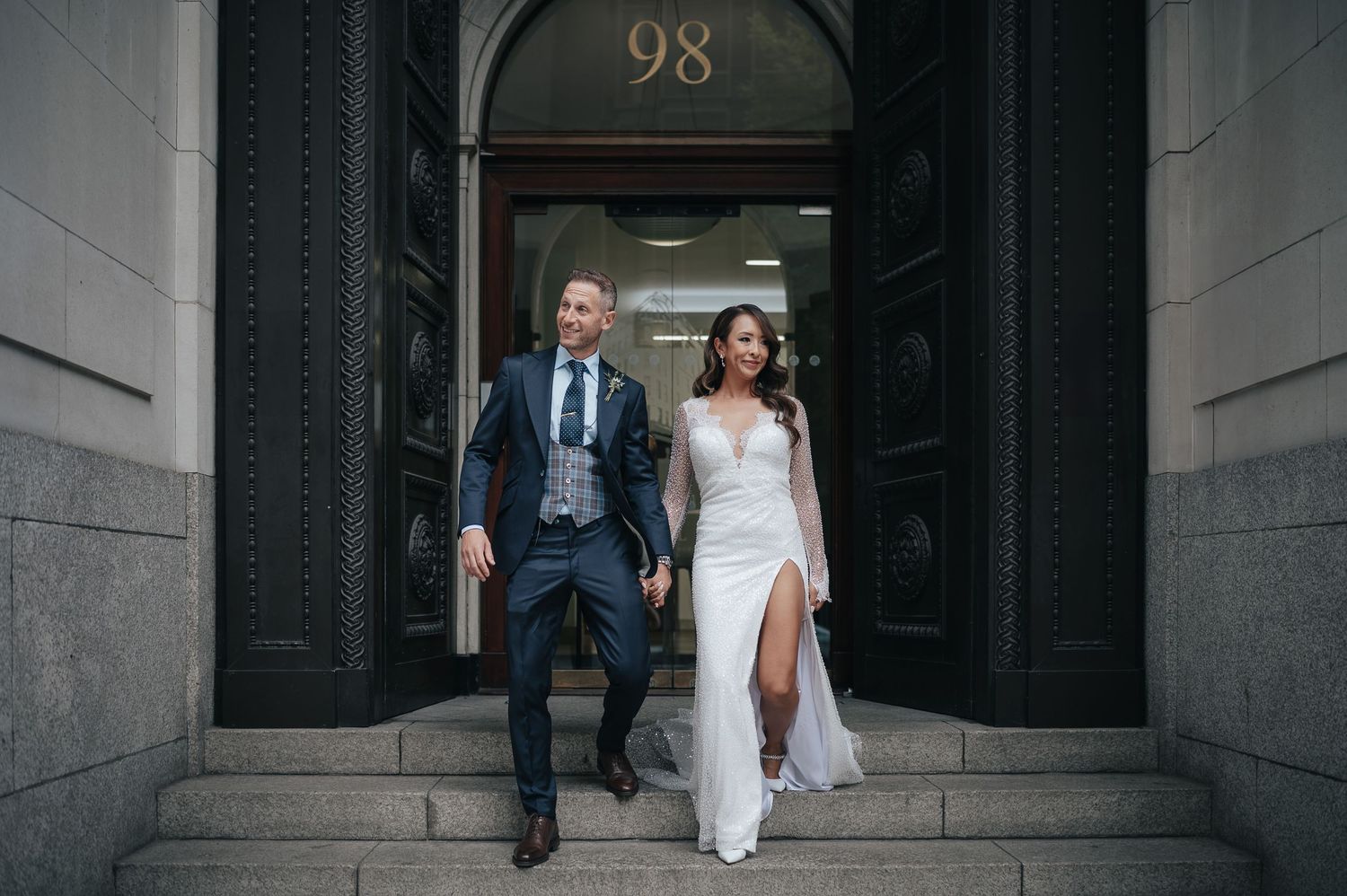 Elegant couple descending stone steps marked with number 98.
