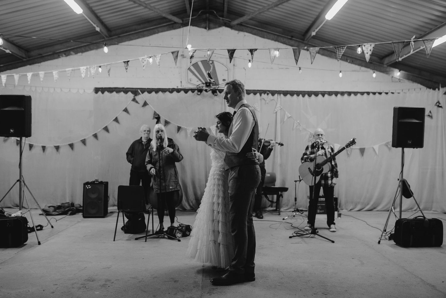 A couple shares their first dance while a band performs at their wedding reception.
