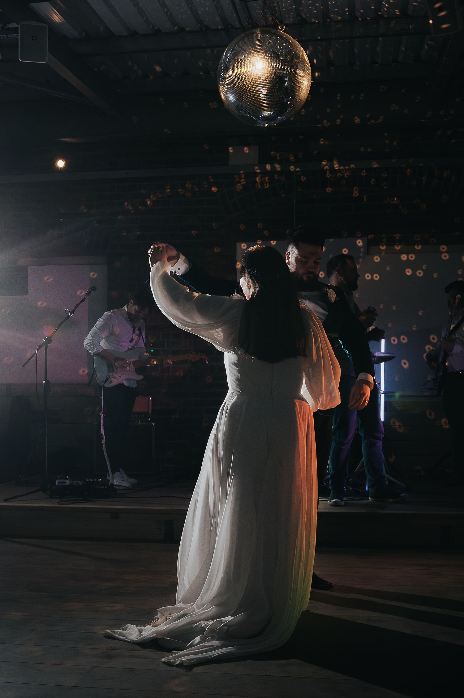 Couple sharing their first dance under a disco ball at their wedding reception.