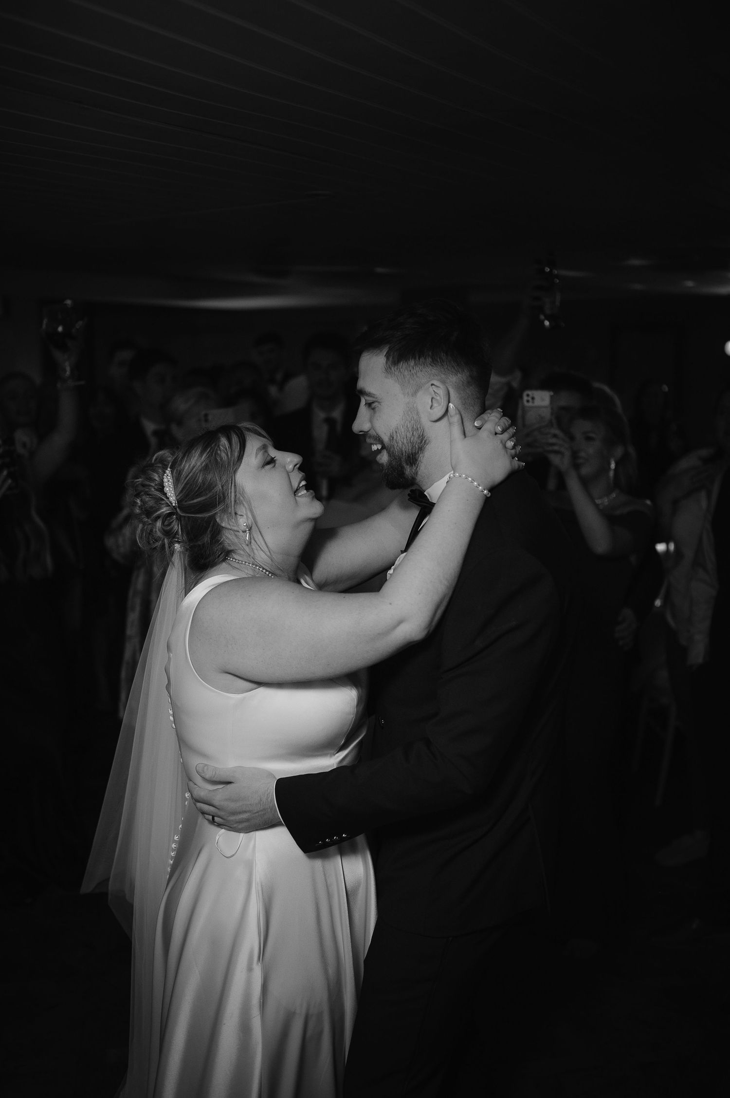 Black and white photo of a newlywed couple sharing an intimate first dance at their wedding reception.