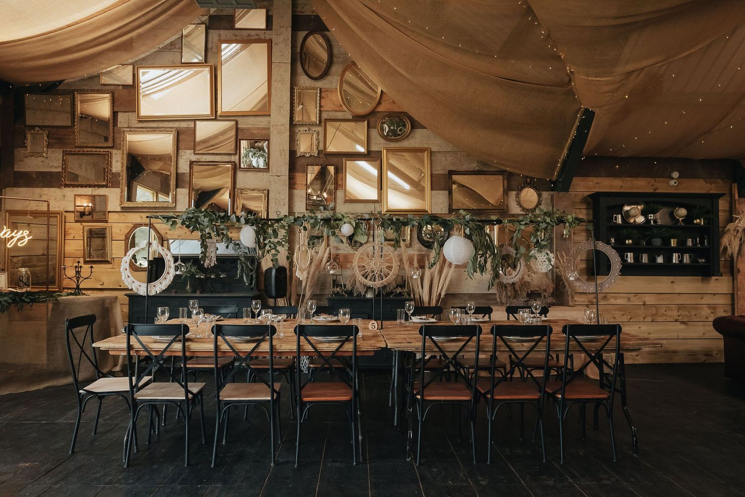 Rustic wedding reception venue with wooden tables and chairs set for dinner.