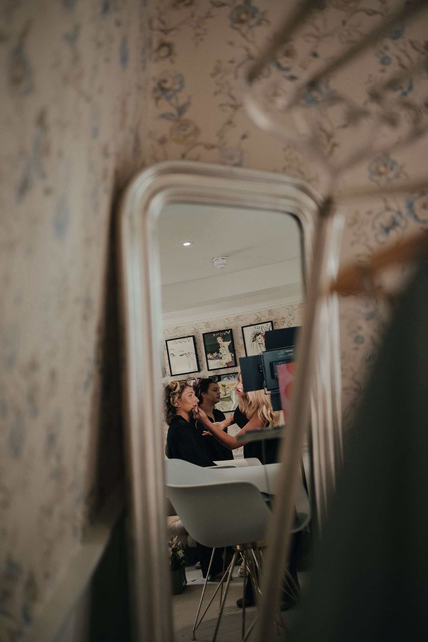 A reflection in a vintage mirror shows wedding preparation activities.