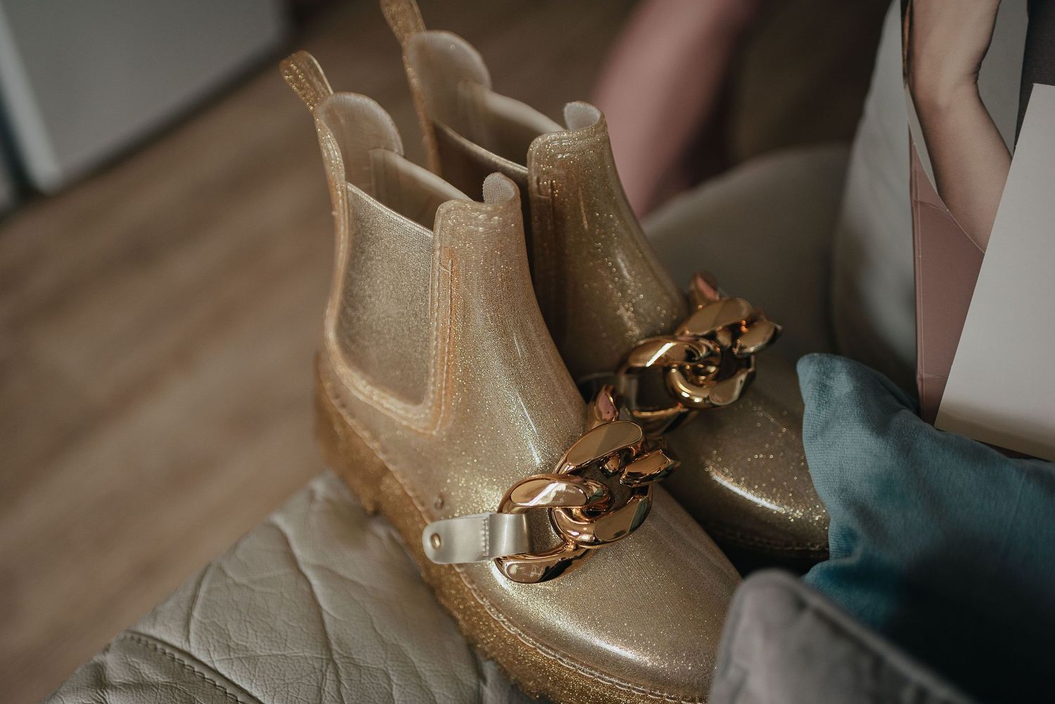 Beige Chelsea boots with gold butterfly decorations on light background.