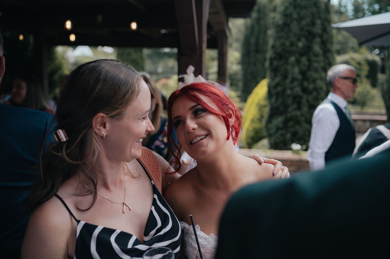 Two wedding guests sharing a laugh and embracing during the celebration.