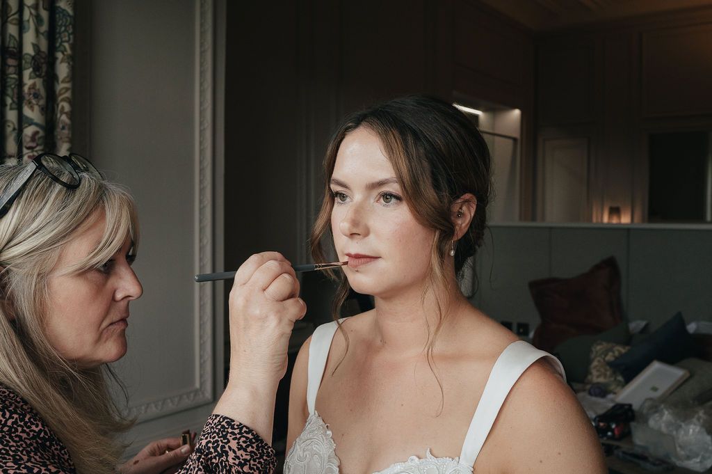 Wedding preparations in progress with styling assistance in a dimly lit room.