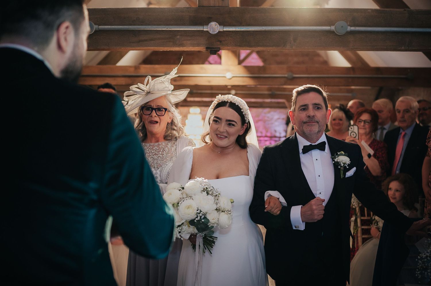 A wedding ceremony taking place in a rustic wooden beam venue with guests in attendance.
