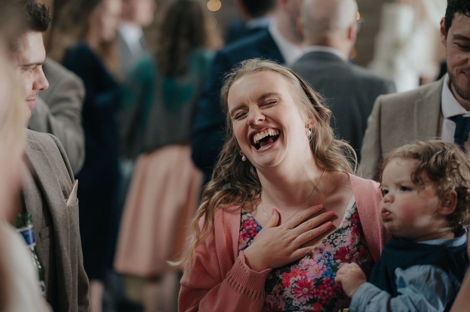 Wedding guest laughing joyfully during reception celebrations.