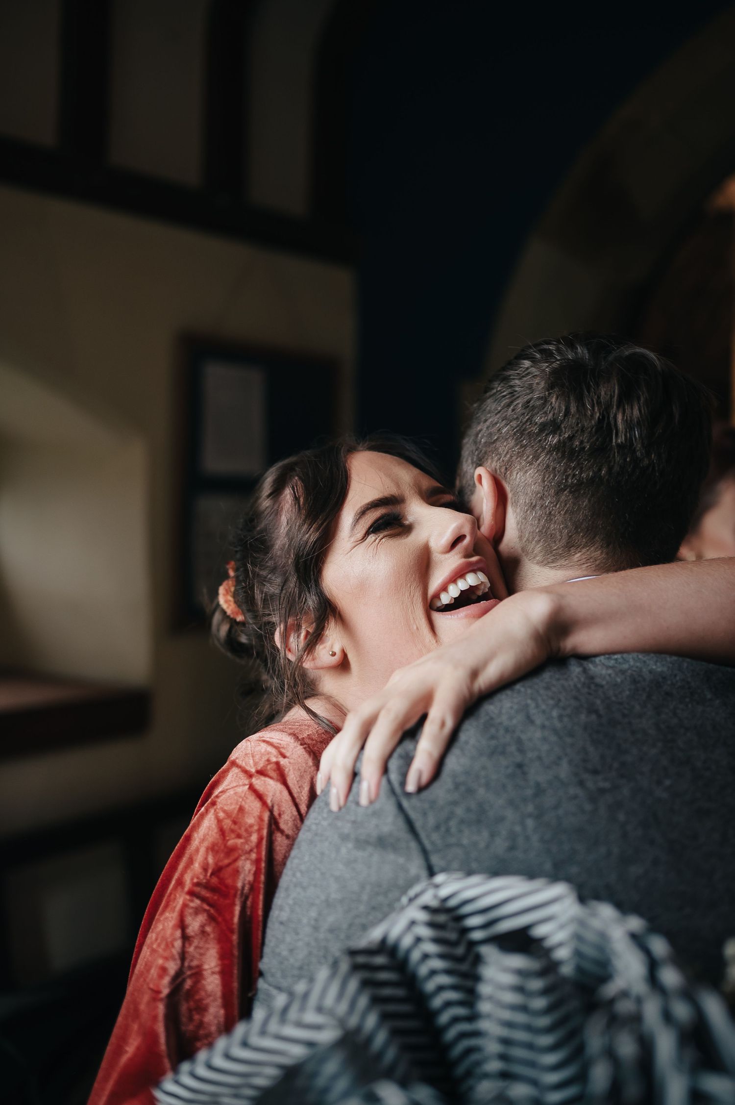 A joyful embrace captured in dramatic lighting during a wedding celebration.