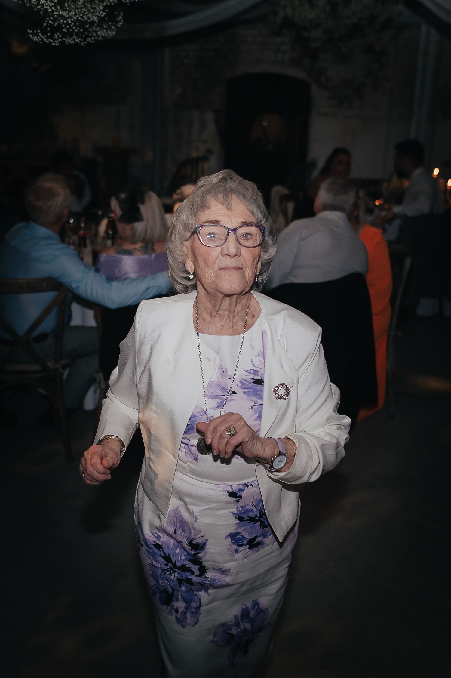 Guest in floral dress dancing at wedding reception.