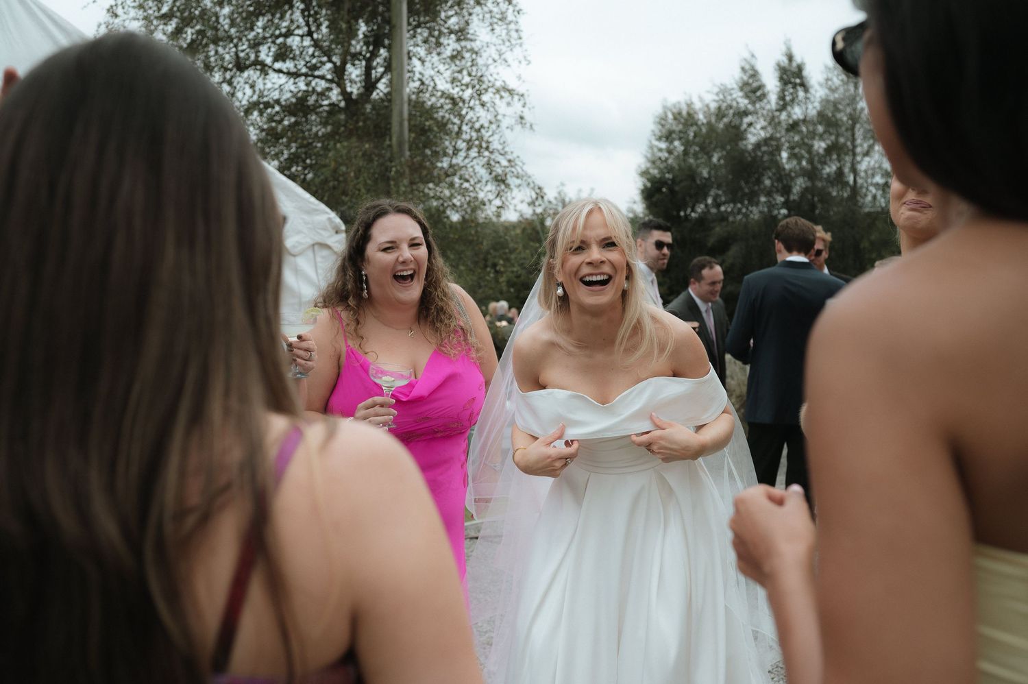 A group of people celebrating at an outdoor wedding event with a mix of formal attire and casual dress.