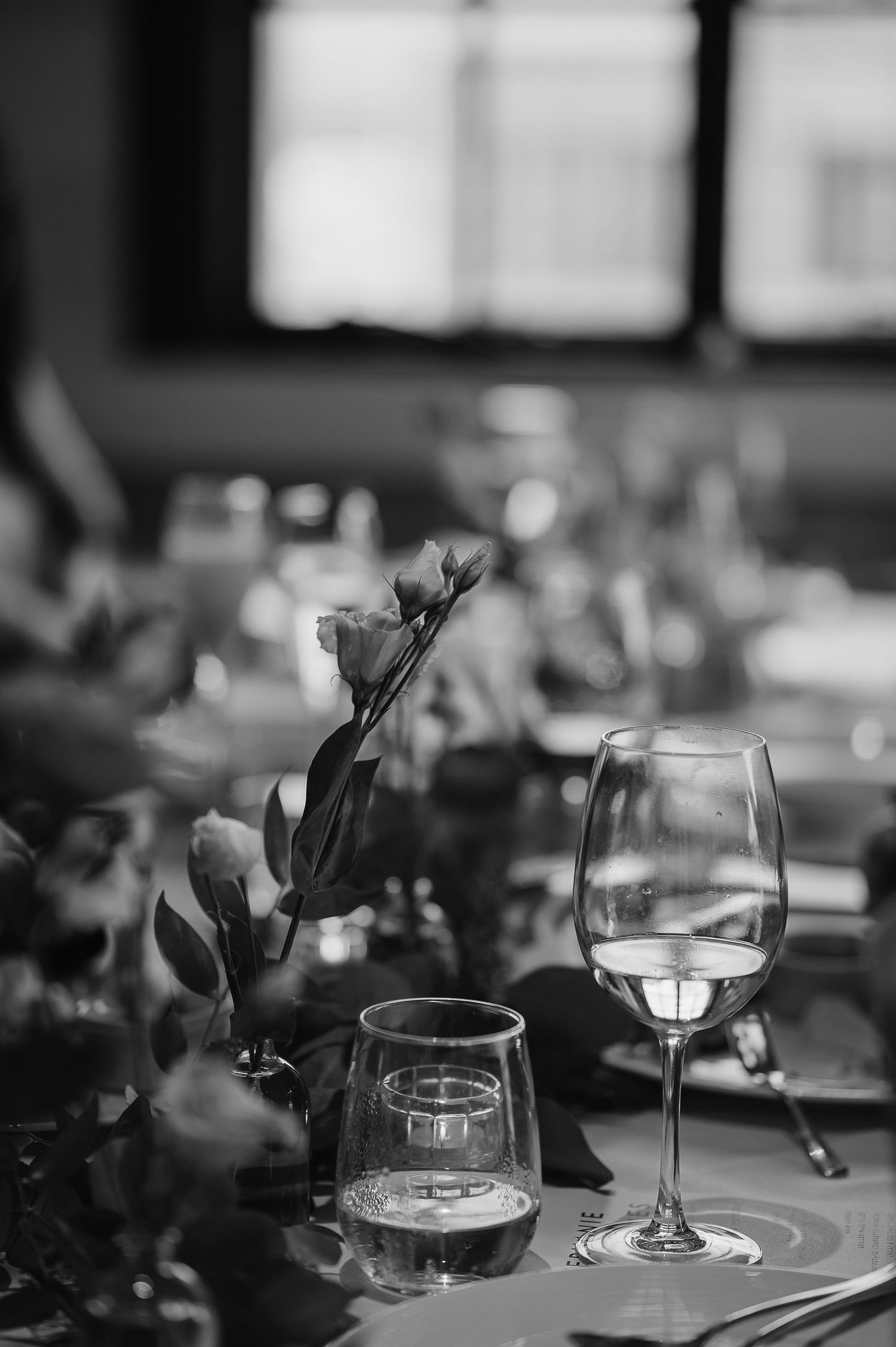 Wedding reception table setting with wine glasses and floral centerpiece in black and white.