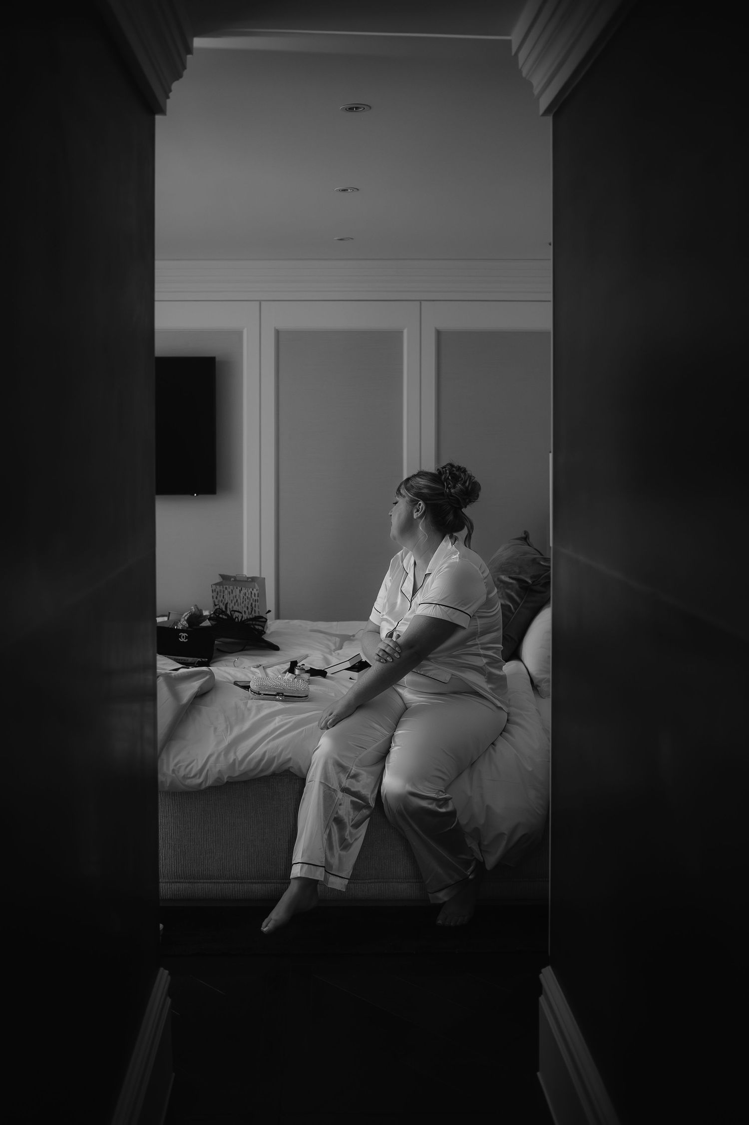 A serene moment captured in black and white as someone sits on a bed by a window in morning light.