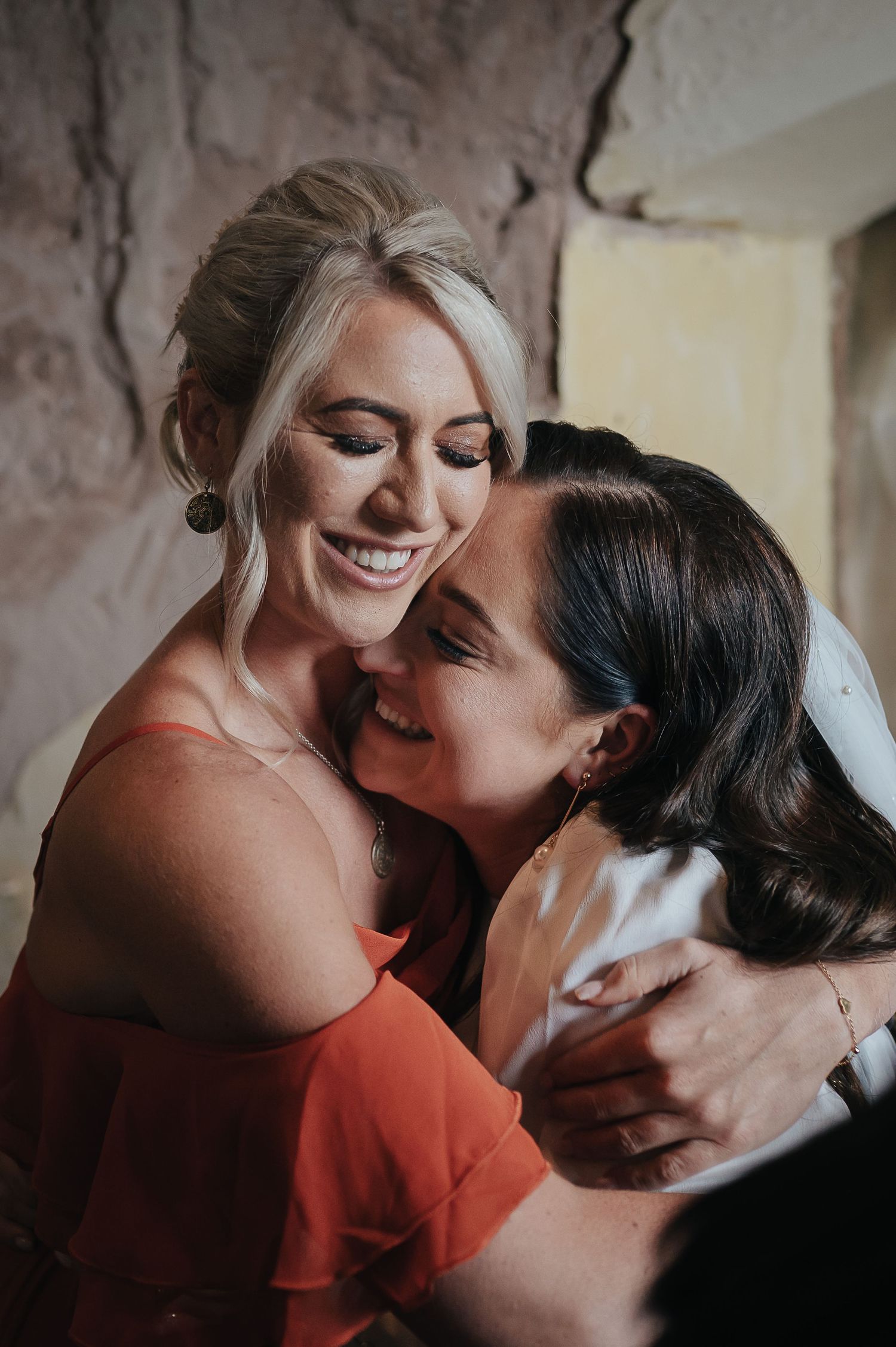 Two people share an intimate embrace while wearing red and light colored formal attire.