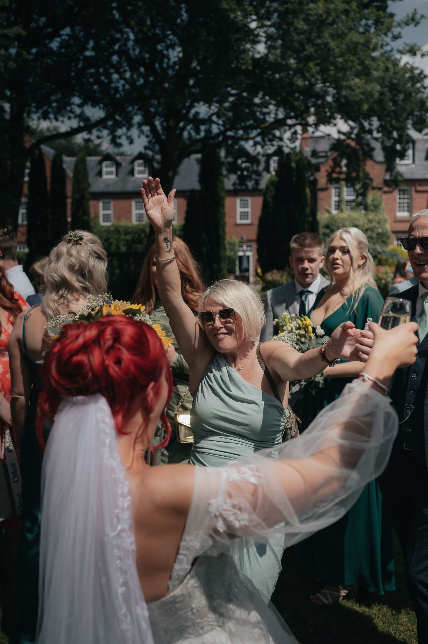 Wedding celebration with guests dancing and celebrating outdoors.