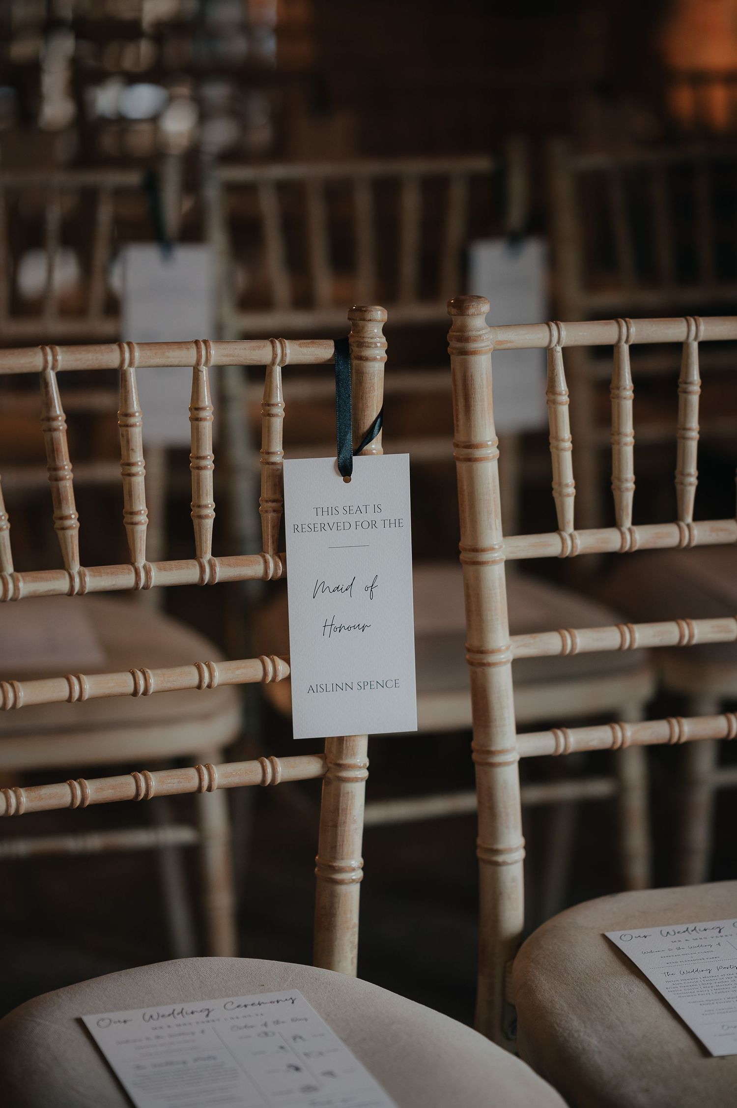 Wedding ceremony seating with elegant wooden chairs and reserved seating cards.