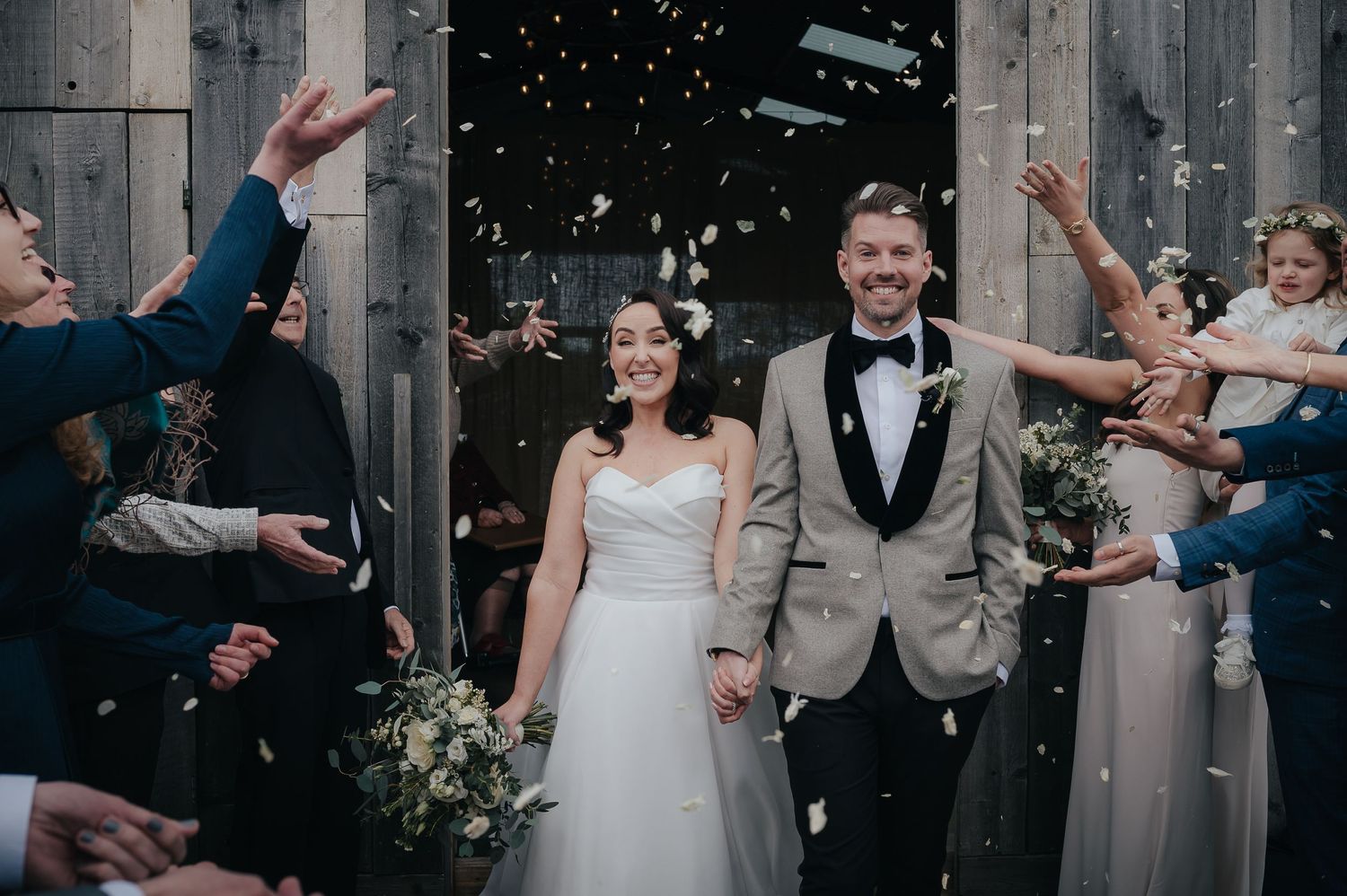 Newlyweds exit ceremony while guests throw confetti in celebration.