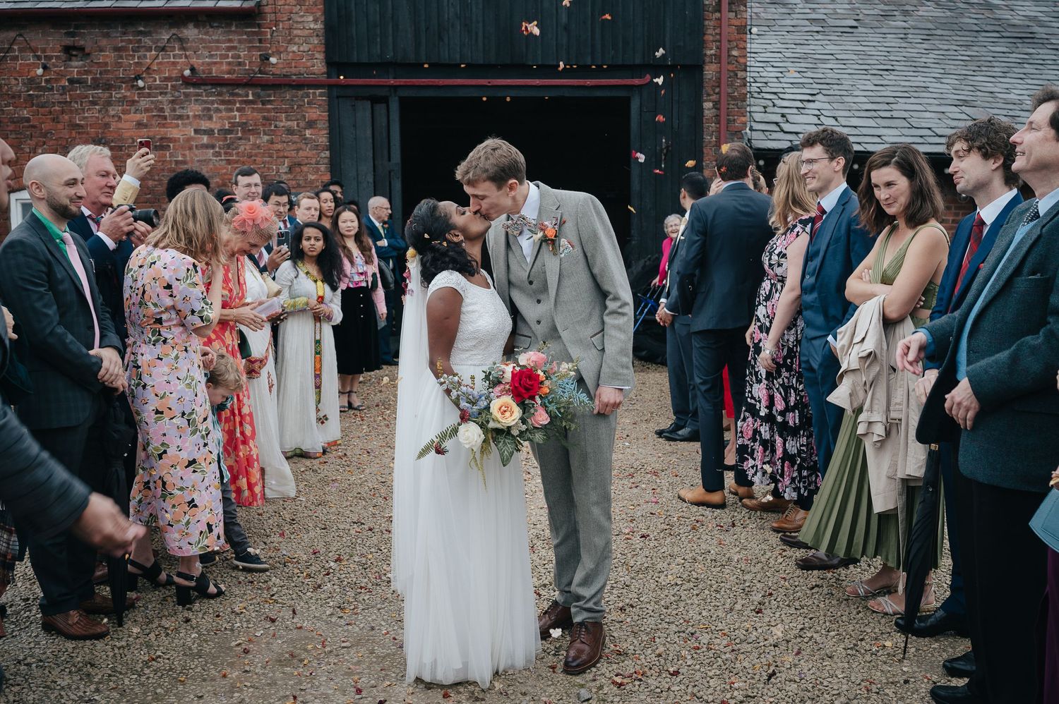 Newlyweds walking through a crowd of guests on a gravel path.
