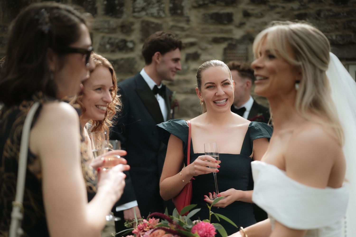 Wedding guests and party members socializing at an outdoor stone venue.